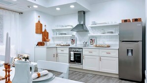 A modern kitchen with white cabinetry, a stainless steel refrigerator, and a built-in oven.