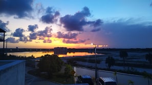 Un coucher de soleil sur une étendue d’eau, avec des bâtiments en arrière-plan.