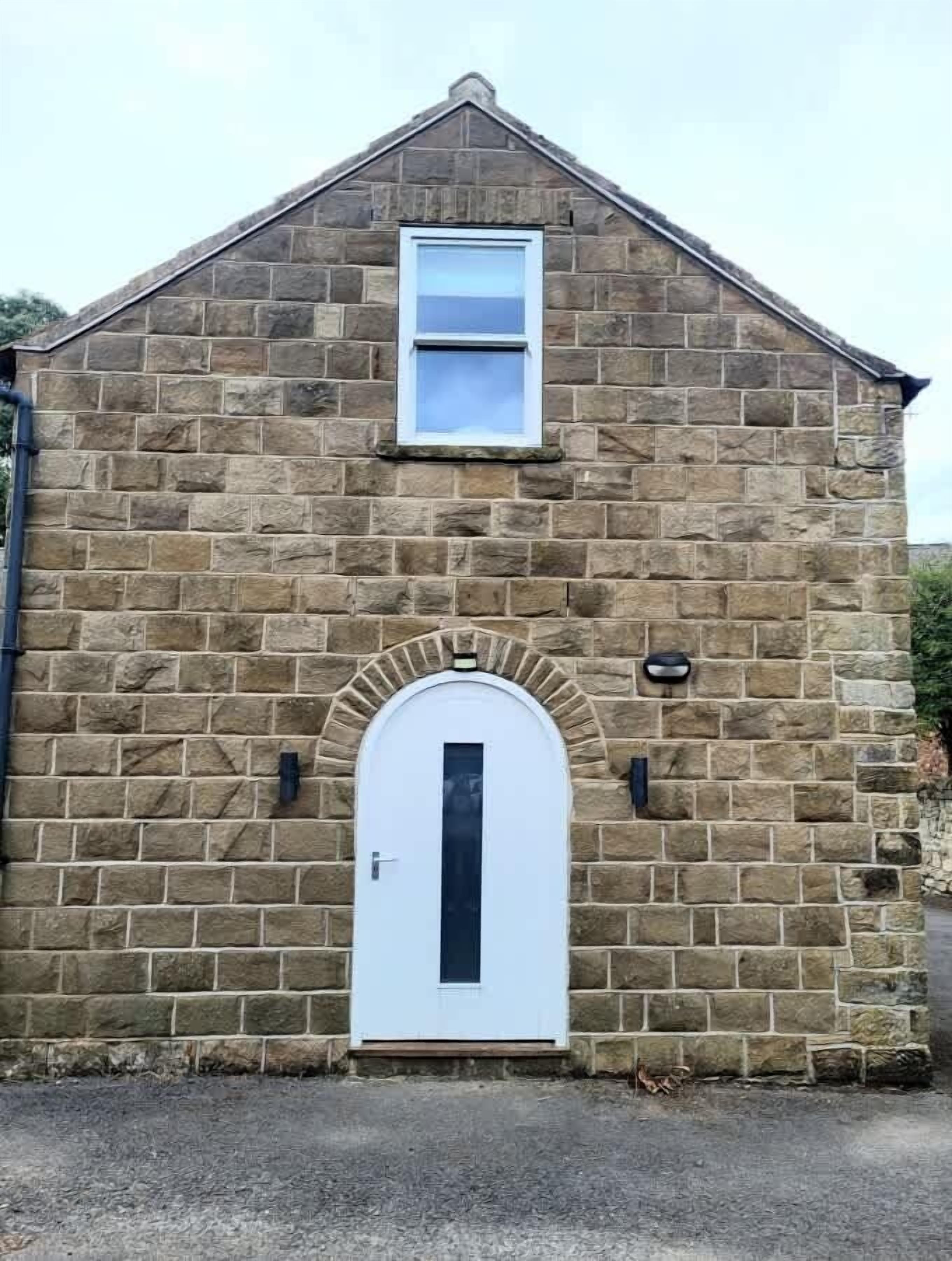 Un edificio de piedra con una puerta blanca y una ventana pequeña.
