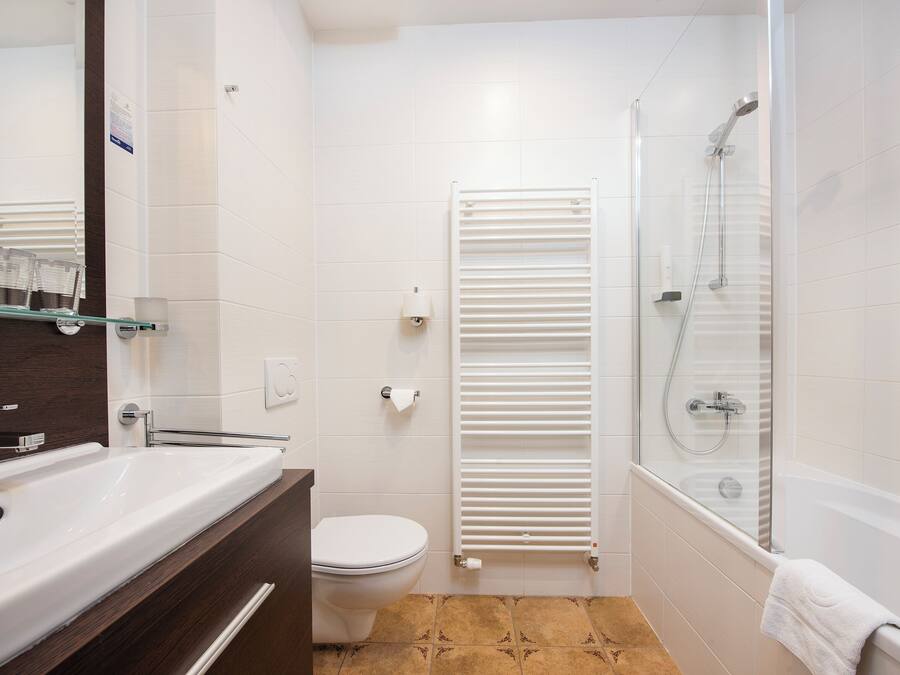 Un baño moderno con lavamanos, inodoro y ducha blancos.