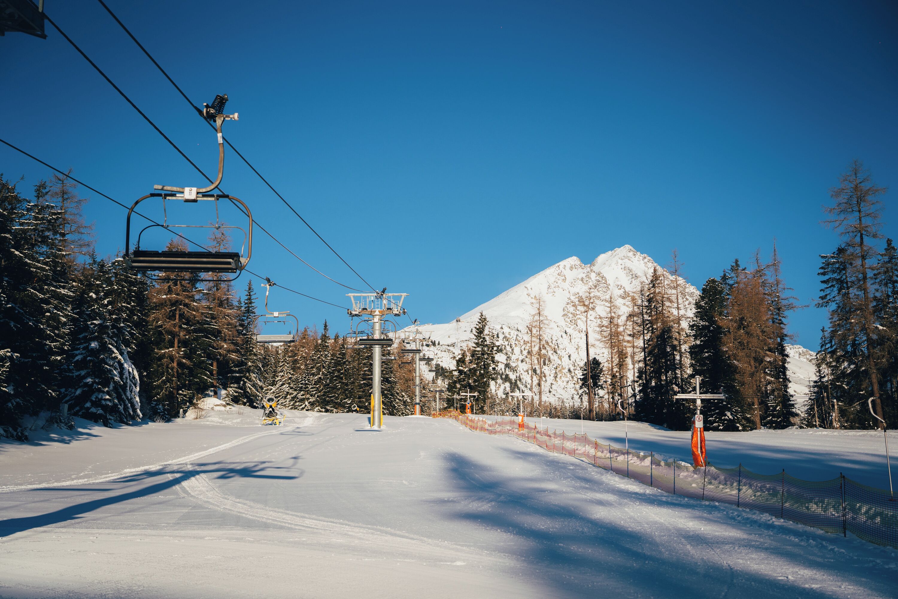 Une piste de ski enneigée, avec un télésiège et une montagne en arrière-plan.