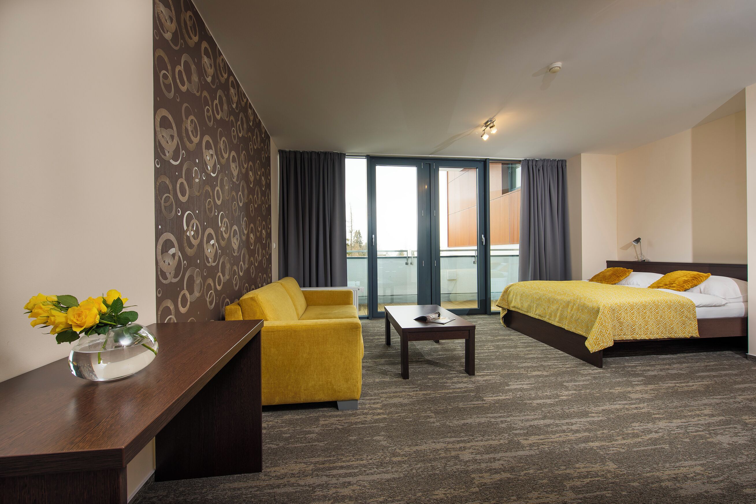 Habitación de hotel con cama, sofá, escritorio y un amplio ventanal.