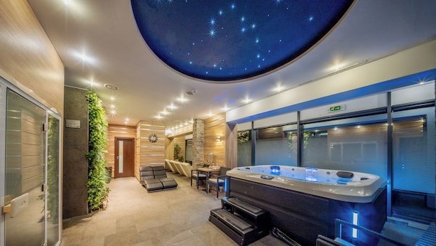 Un espace spa comprenant un bain à remous, des sièges et un plafond décoré d’étoiles.