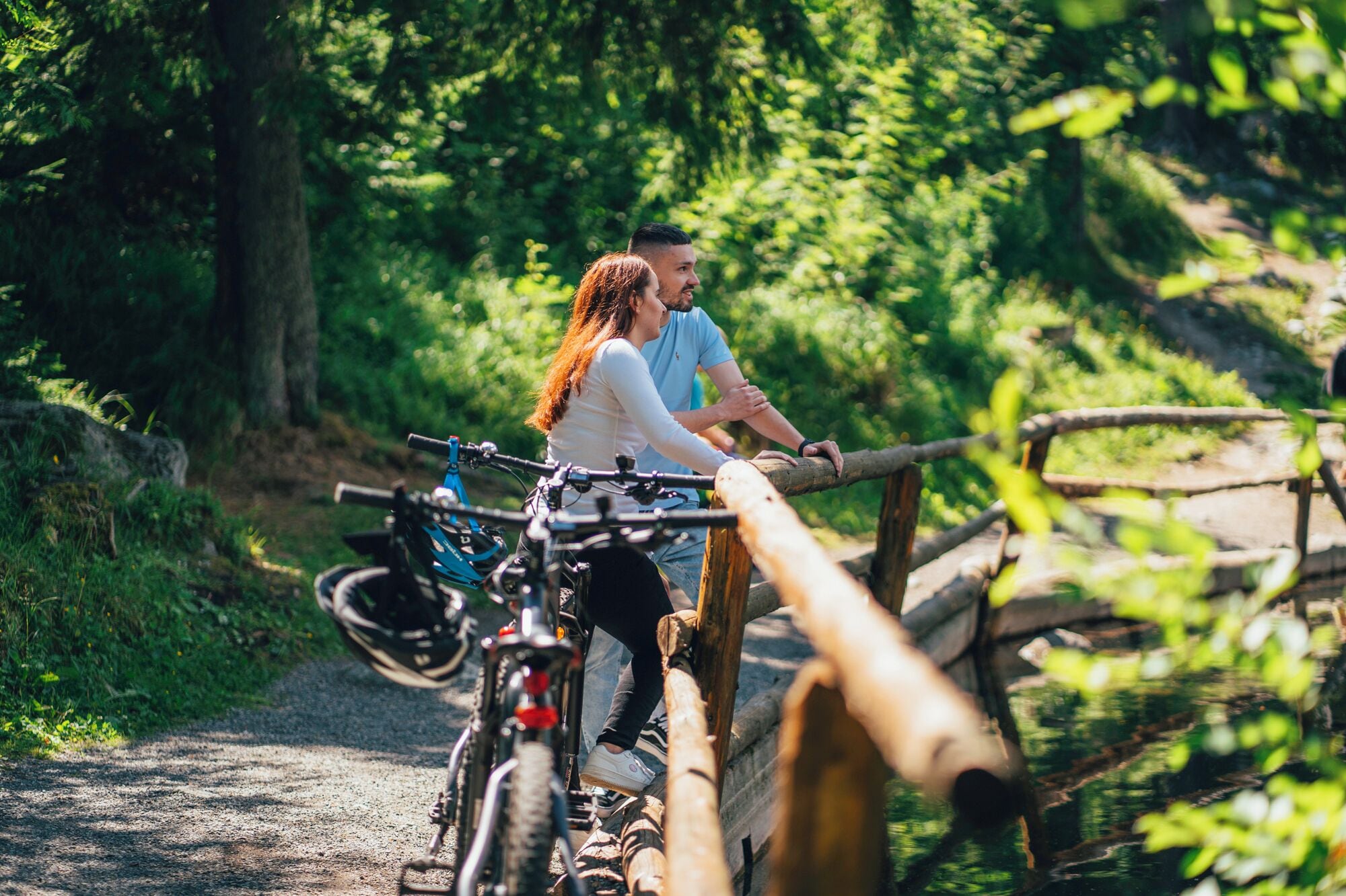 Una pareja en un sendero para bicicletas, con bicicletas y una valla de madera.
