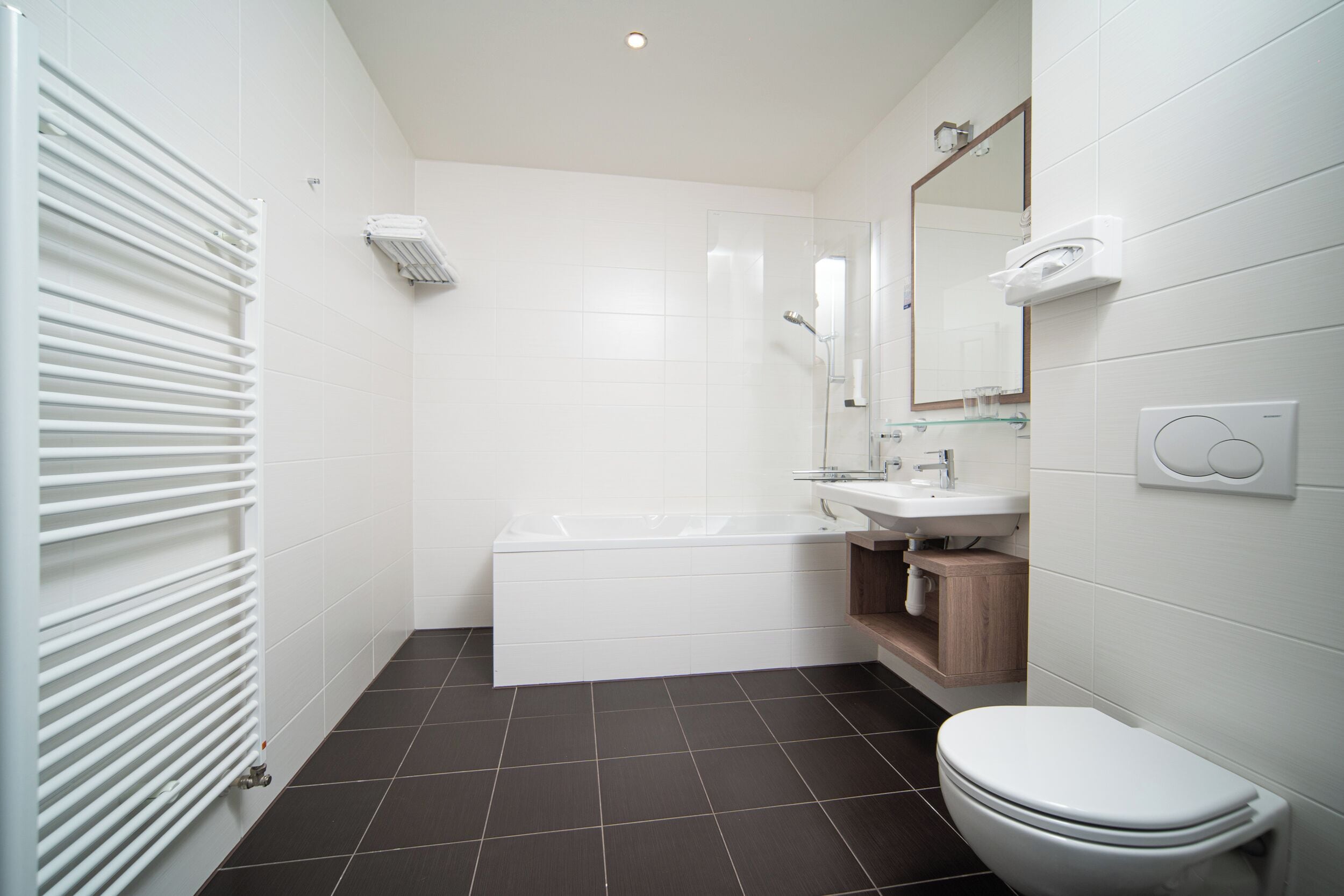 Een moderne badkamer met een bad, toilet, wastafel en spiegel.