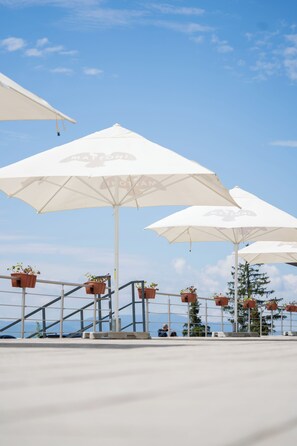 Outdoor umbrellas with potted plants, metal railings, and a clear sky. - Hotel Panorama (Štrba)