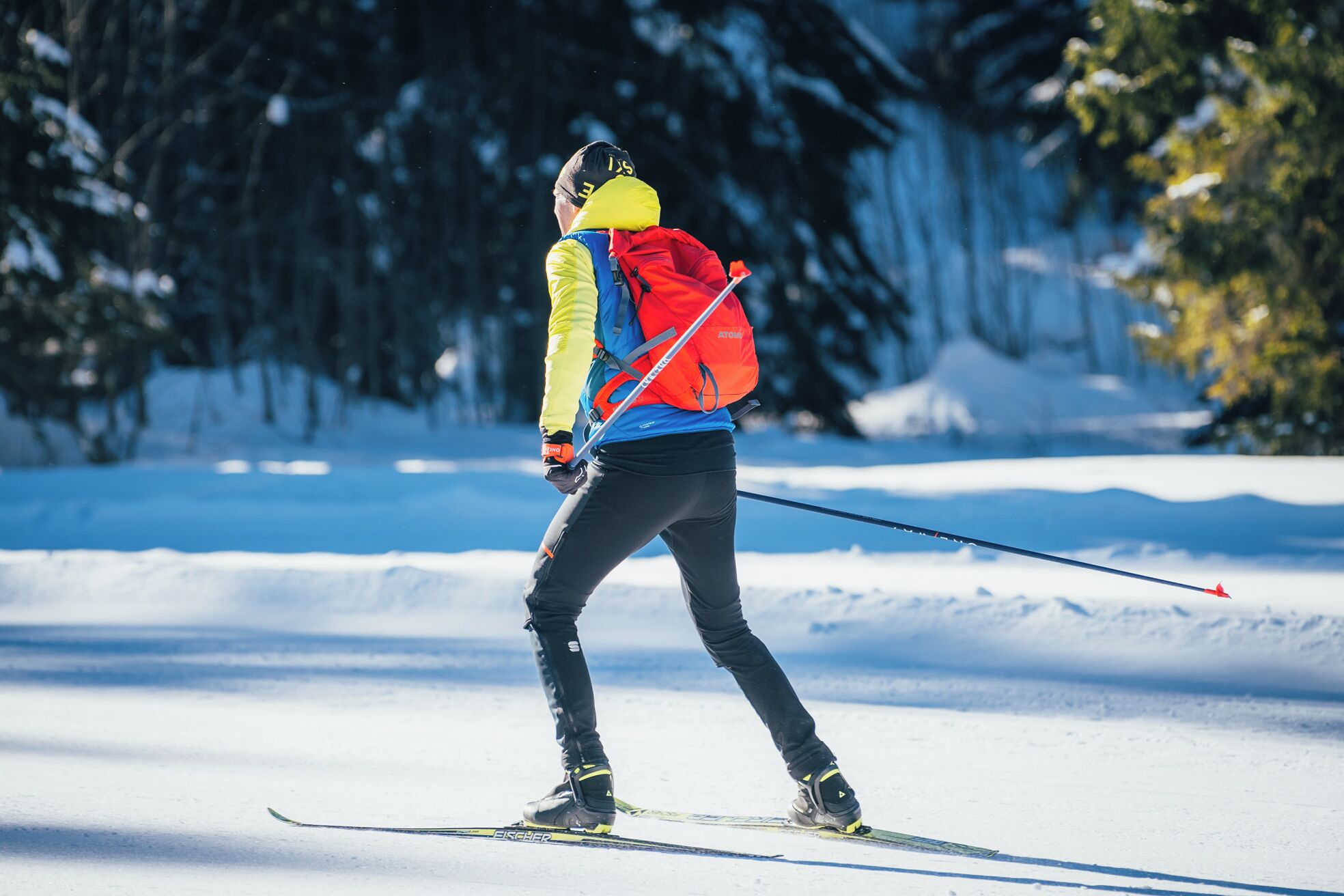 Una persona esquiando en un sendero nevado con árboles al fondo.