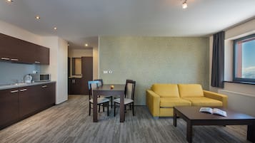 Un espacio habitable moderno con comedor, un sofá amarillo y una cocina con armarios de madera oscura.