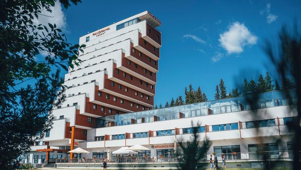 A modern hotel with multiple floors, outdoor seating, and a prominent sign.