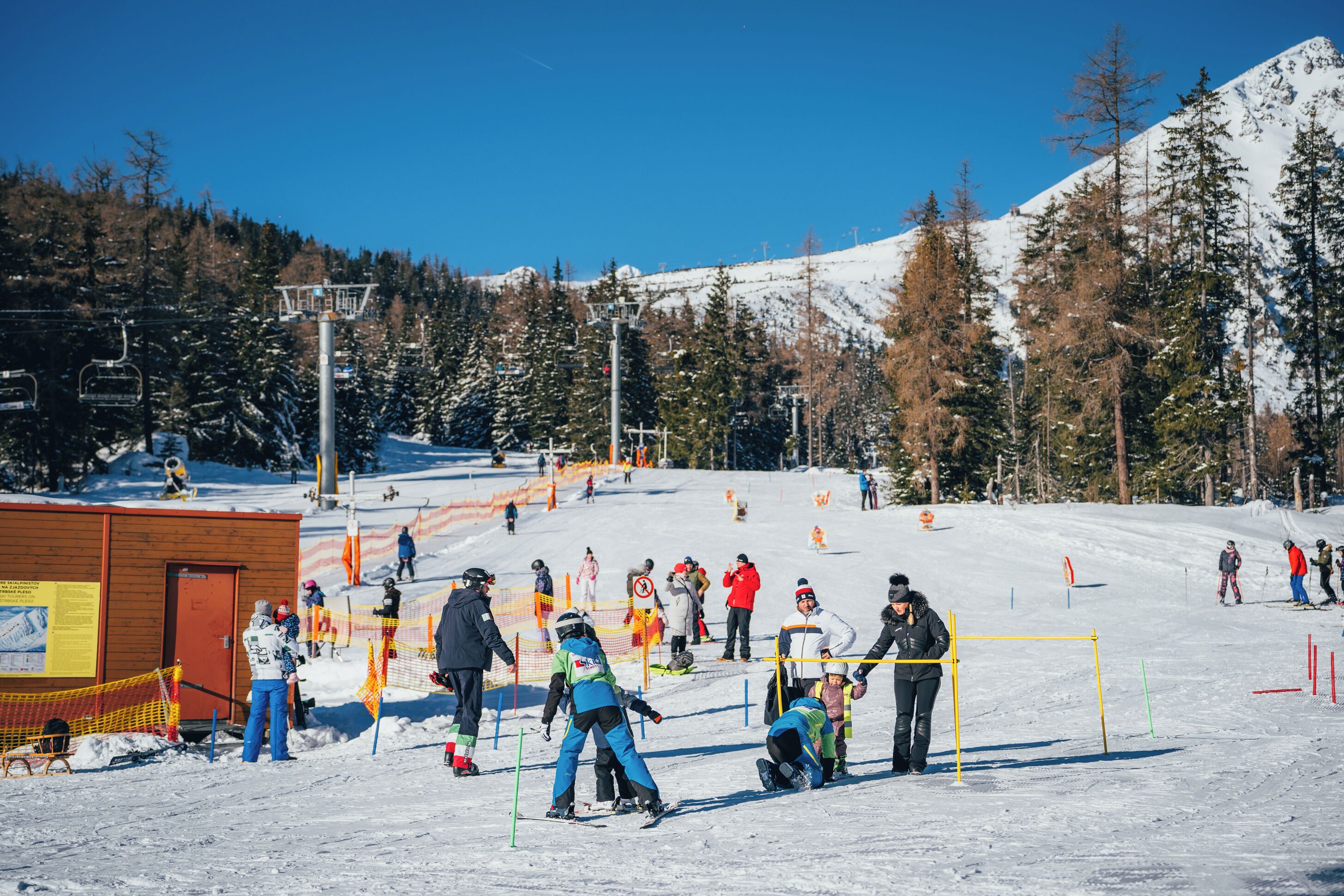 A ski resort with a ski lift, snow-covered slopes, and a wooden building.