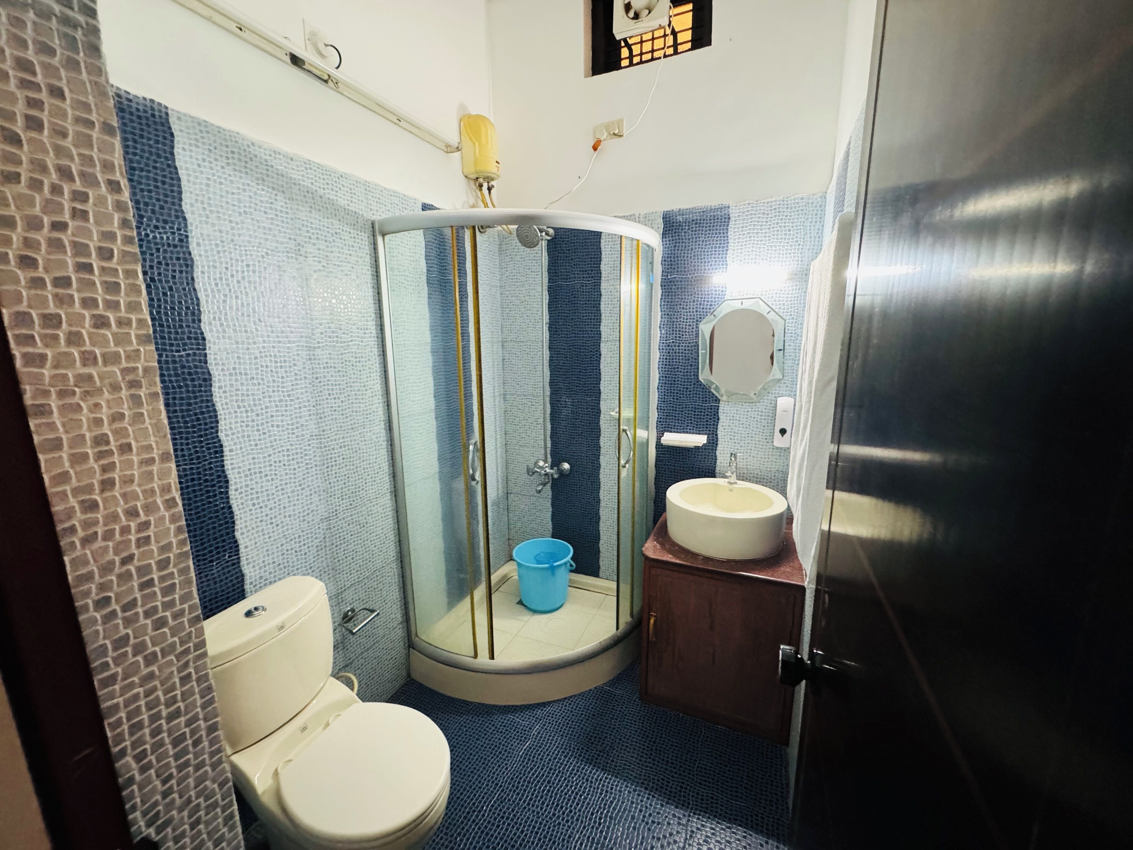 A bathroom with a glass-enclosed shower, a toilet, a sink, and a mirror.