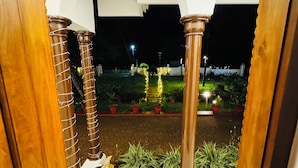 An entrance with a tiled floor, wooden pillars, and potted plants. - Coconut Creek Homestay (Kottayam)