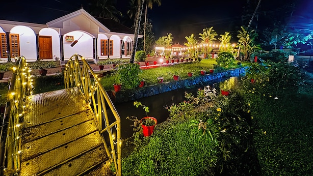 A well-lit building with multiple arches and a bridge leading to it. - Coconut Creek Homestay (Kottayam)