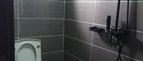 Un baño pequeño con azulejos, que incluye un inodoro, un bidé y una ducha.