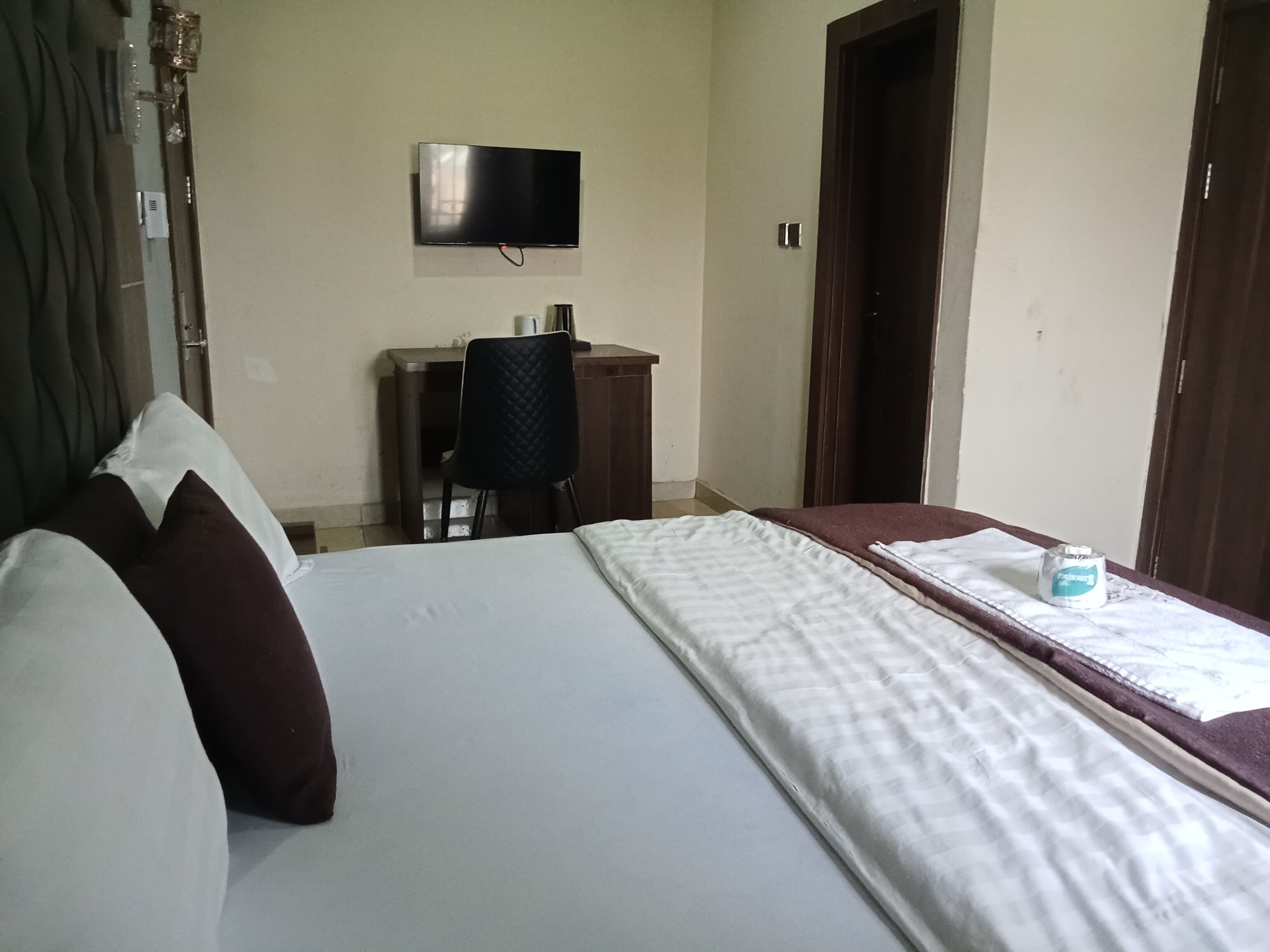 Ein Hotelzimmer mit Bett, Schreibtisch, Stuhl, Fernseher und einer Tür.
