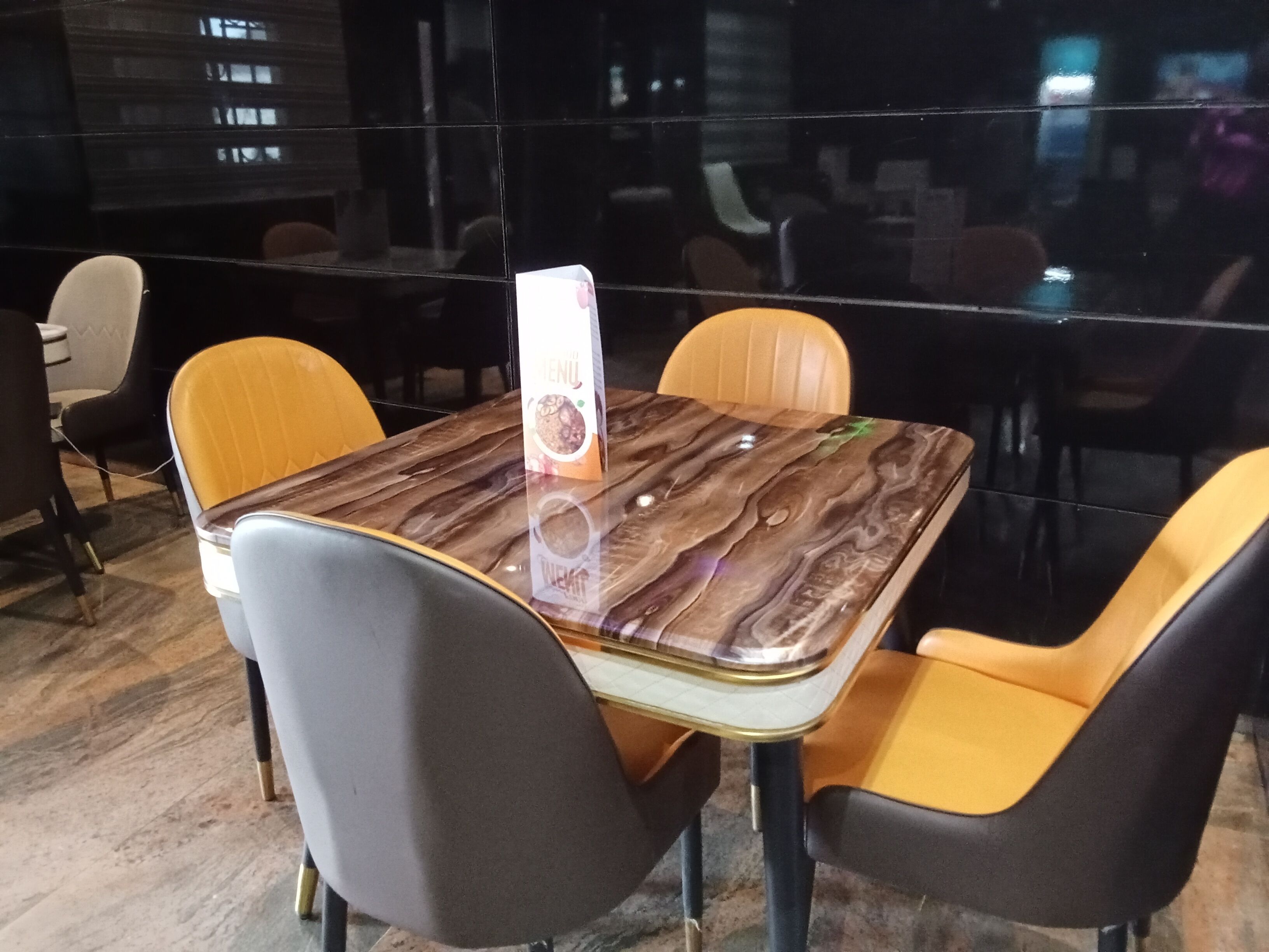 Een eetruimte met een marmeren tafel en vier stoelen, waarvan er één een menu heeft.