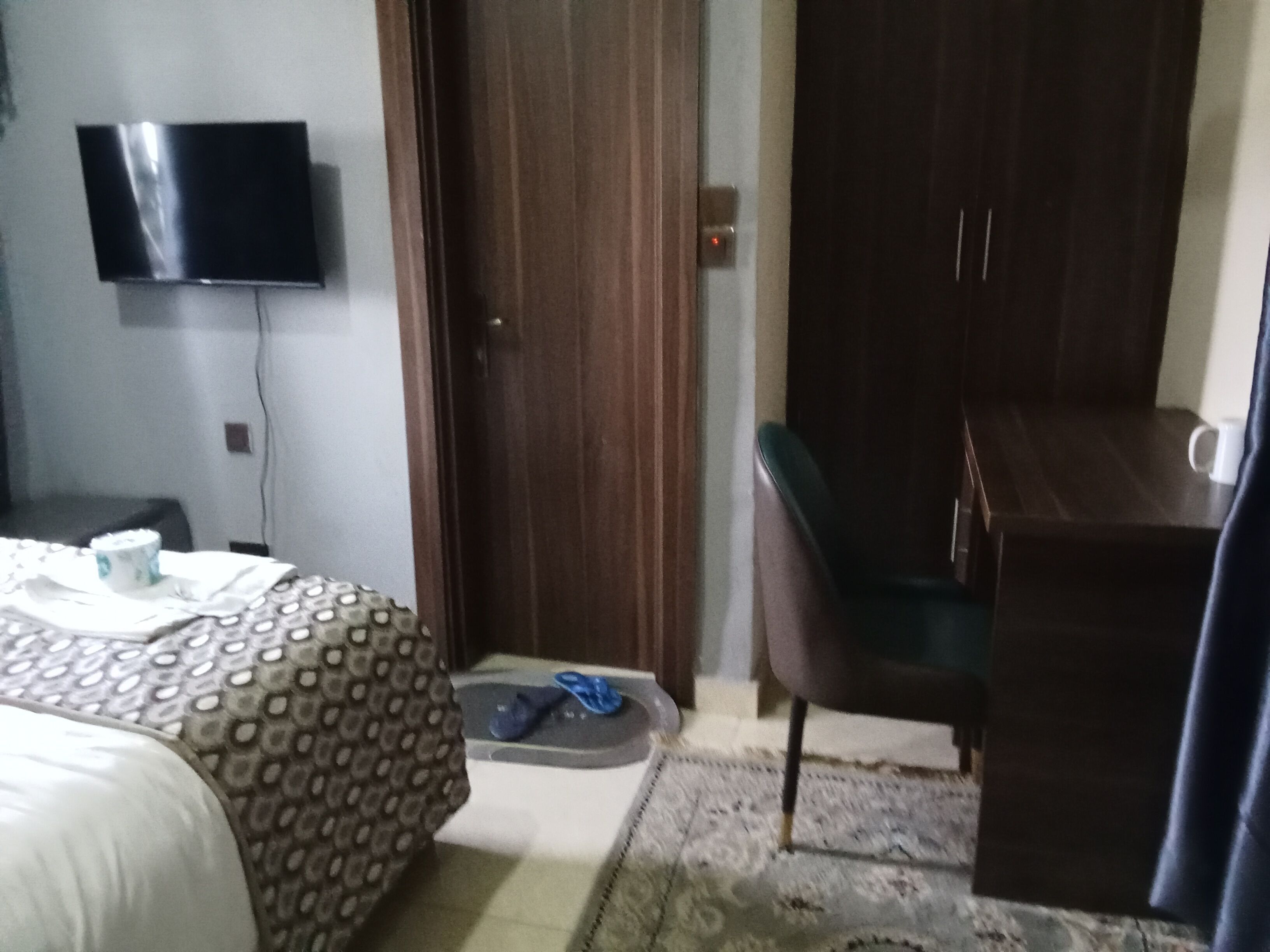 A hotel room with a bed, a desk, a chair, a television, and a door.