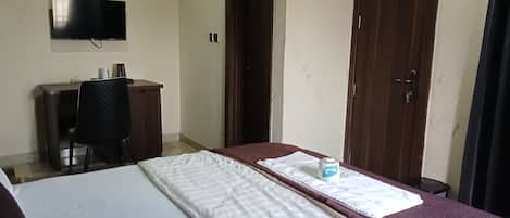 Una habitación con una cama, un escritorio, una silla y un televisor en la pared.