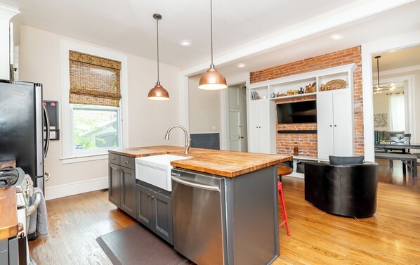 Una cocina moderna con una isla central, electrodomésticos de acero inoxidable y una pared decorativa de ladrillo.