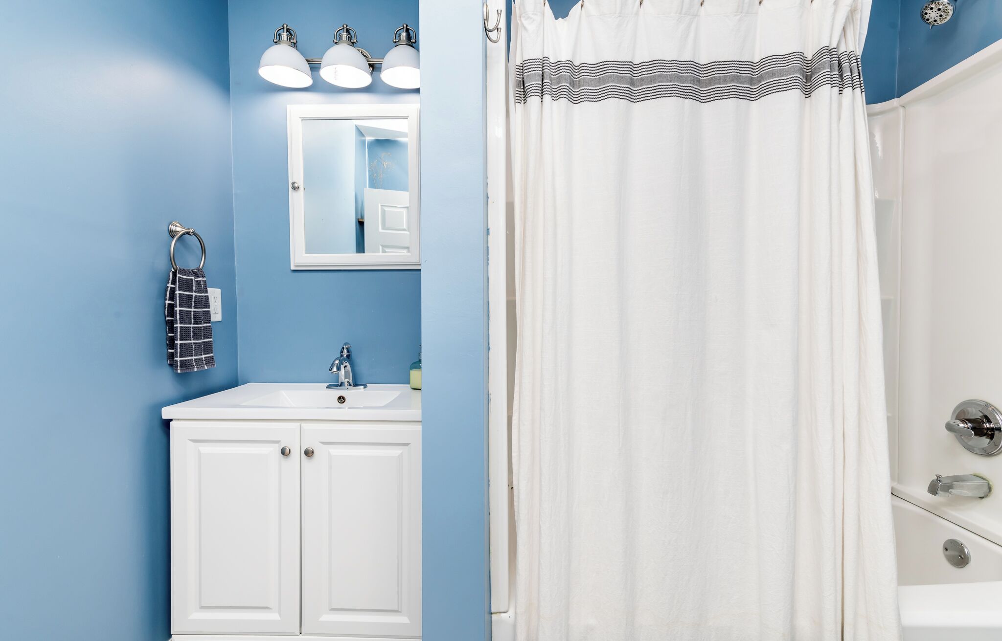 A bathroom with a white sink, a mirror, and a shower curtain.