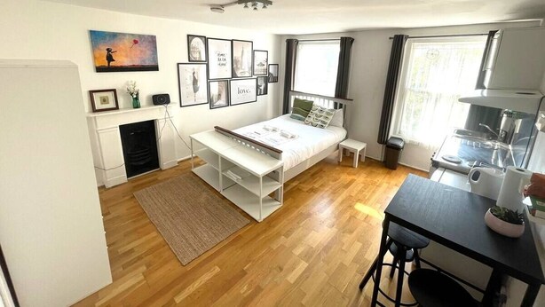 A compact bedroom with a bed, bedside table, and a small desk area. - Charming studio apartment in Central London W2 (London)