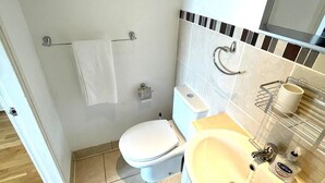 A bathroom with a toilet, sink, and mirror. There are two framed pictures on the wall. - Charming studio apartment in Central London W2 (London)