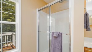 A bathroom with a glass shower enclosure, a window with a view of a deck, and a towel hanging on the shower door. - New! Lakefront, Great Location, Pet Friendly (Henrico)