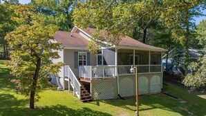 A two-story house with a covered porch, a small front yard, and a tree. - New! Lakefront, Great Location, Pet Friendly (Henrico)