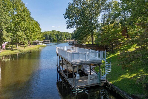A docked boat on a calm river with a grassy bank and trees.