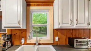 A kitchen with white cabinets, a double sink, and a window.