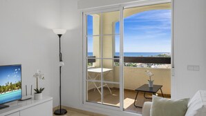 A balcony with a view of the sea, a small table, a chair, and a TV on a stand. - Nice Seaview 2 Bed 2 Bath Apartm. (Benalmádena)