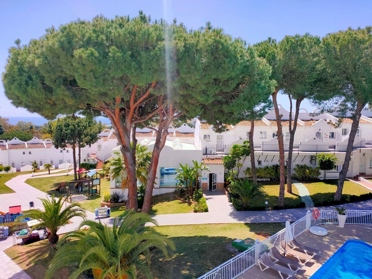 Ein Resort mit Pool, Palmen und einem weißen Gebäude mit Balkonen.
