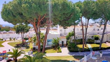 Ein Resort mit Pool, Palmen und einem weißen Gebäude mit Balkonen.