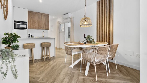 A modern kitchen with a central island, wooden cabinets, and a hanging light fixture. - Casa Rija Mijas village by Casa del sol (Mijas)