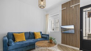 A modern living room with a blue sofa, a round coffee table, and a television mounted on a wooden wall. - Casa Rija Mijas village by Casa del sol (Mijas)