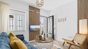 A modern living room with a blue sofa, a round coffee table, a wicker chair, and a TV on the wall. - Casa Rija Mijas village by Casa del sol (Mijas)