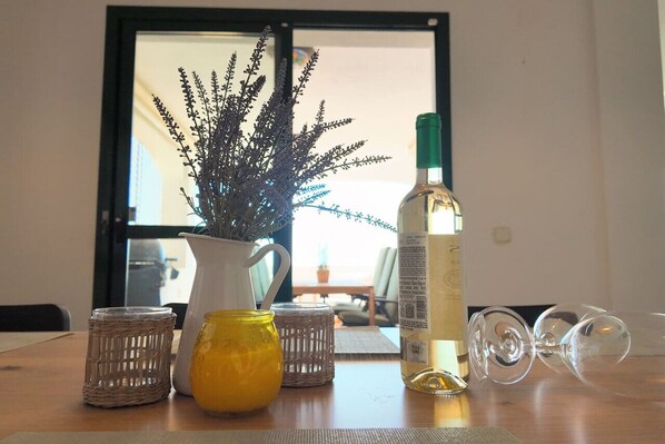 A table with a bottle, a yellow vase, and two glass items.