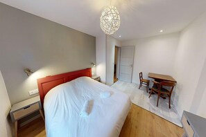 A modern bedroom with a large bed, a desk, and a chair.