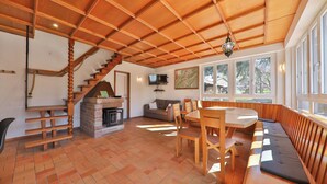 Un vaste espace de vie doté d’un plafond en bois, d’une cheminée, d’un canapé et d’une table à manger.