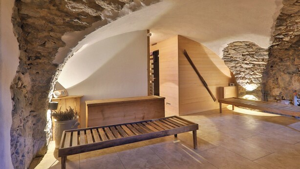 A rustic stone interior with a wooden bench, a wooden cabinet, and a slanted wooden structure. - Luxurious 500 m² villa with vaulted cellar, sauna, spa, large outdoor spaces (Sondernach)