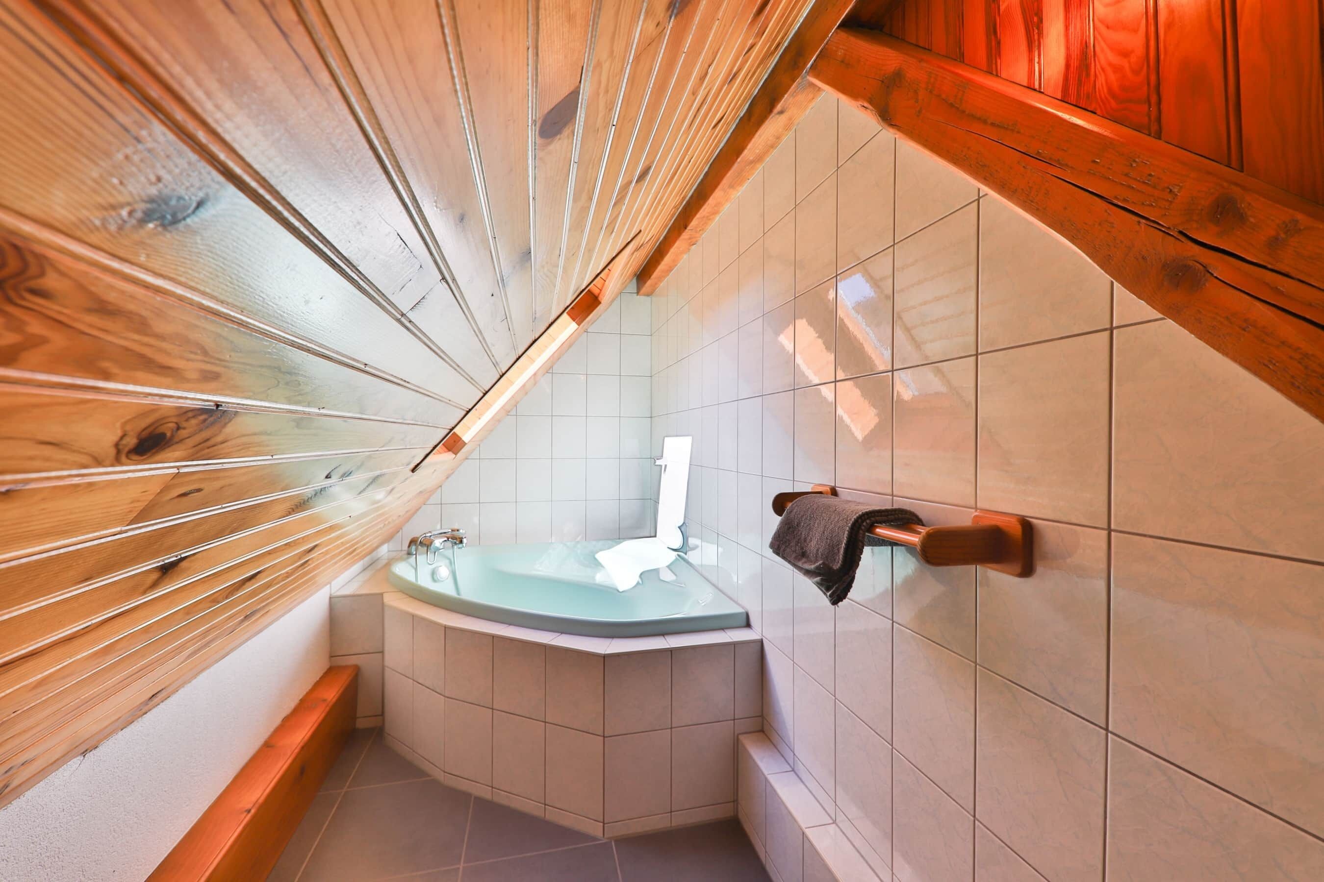 Ein Eckbad mit einer Glaskabine, Holzbalken und Fliesenwänden.