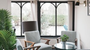 A modern living room with large windows, a round glass table, and several chairs. - BRIT HOTEL CONFORT ORLY MORANGIS (Morangis)