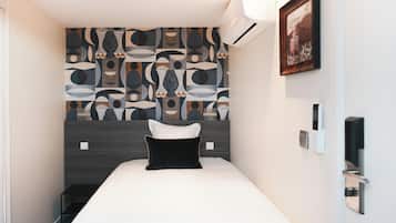 Una habitación de hotel moderna con una cama grande, un papel tapiz estampado, un cuadro y una mesita.