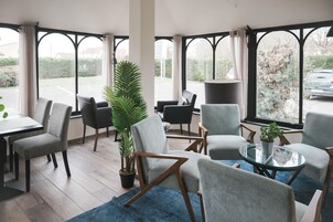 Un área de estar moderna con asientos cómodos, ventanas amplias y una planta en maceta.