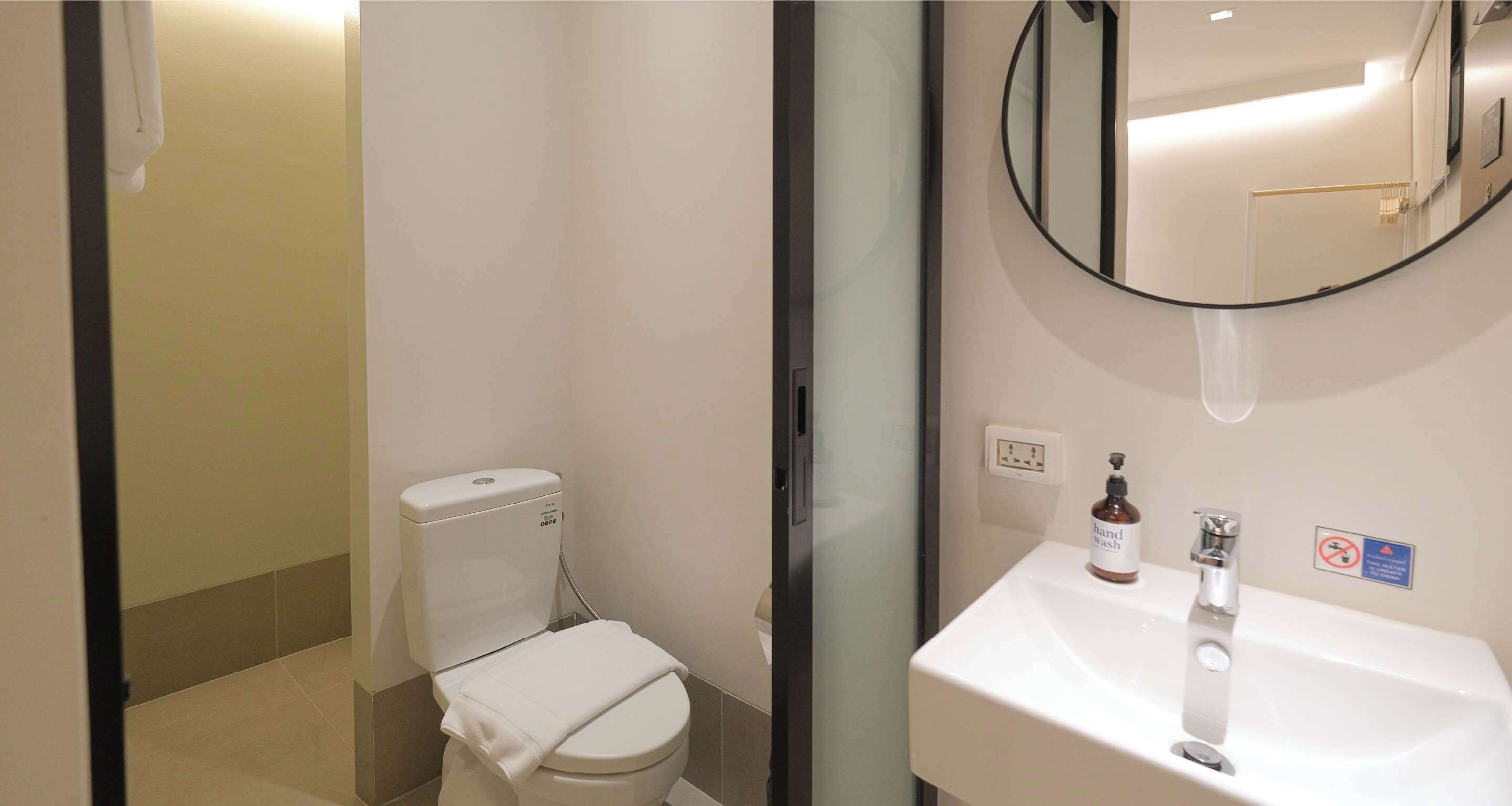 A modern bathroom with a toilet, sink, and a mirror.