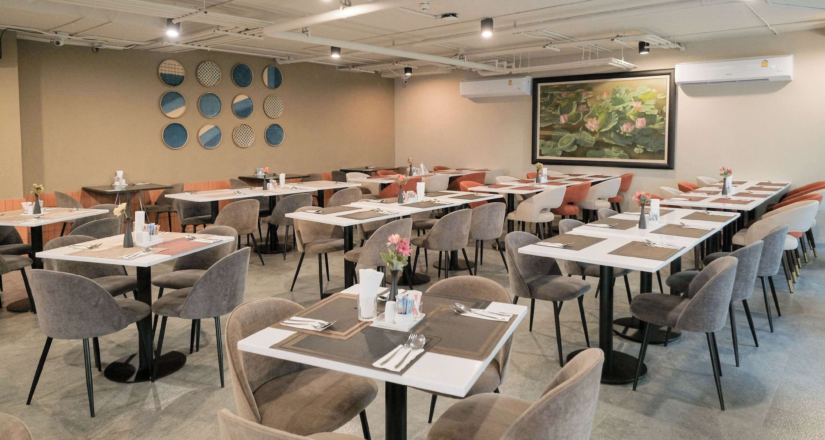 A conference room with multiple tables and chairs, arranged in rows.