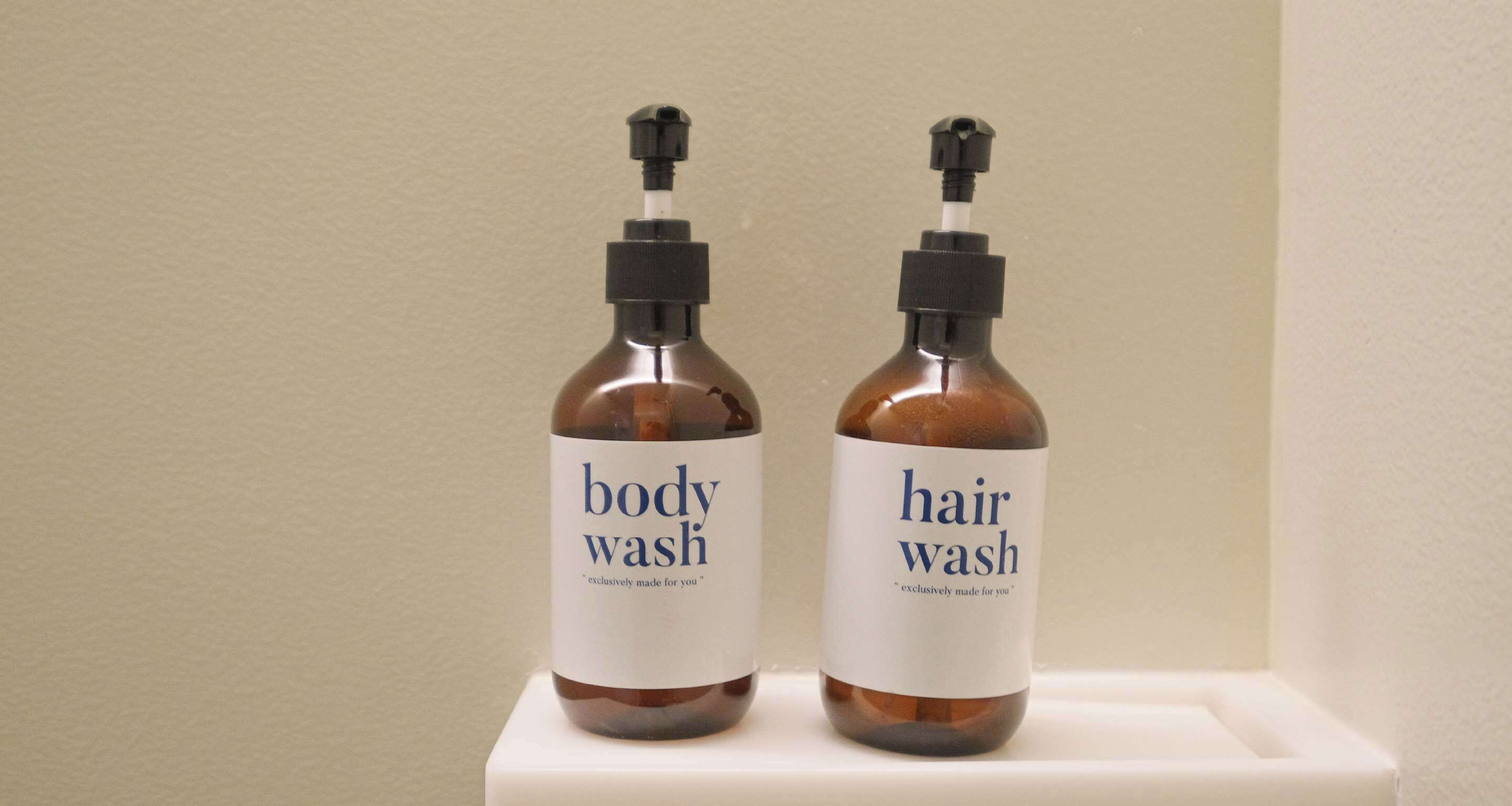 Two bottles of body wash and hair wash on a white shelf.