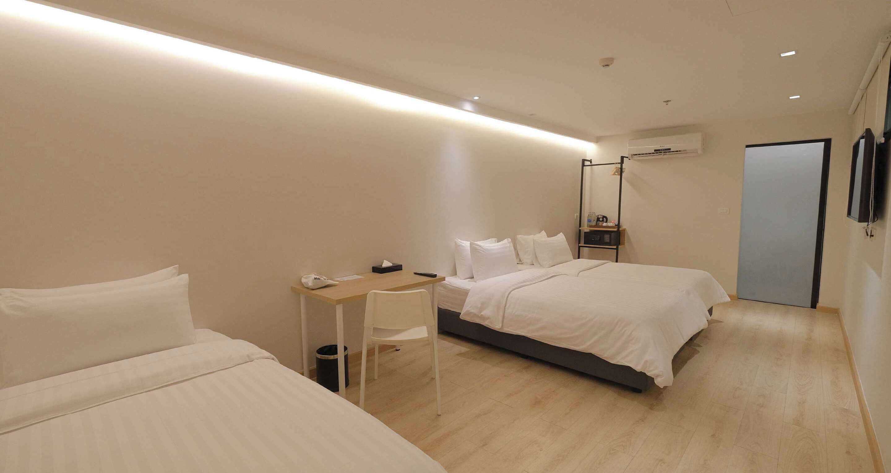 A modern hotel room with a bed, a desk, and a chair.