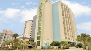 A multi-story hotel with a light green and beige facade, featuring a prominent vertical blue stripe. - New Listing! Meridian Plaza Resort #606 (Myrtle Beach)