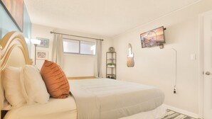 A bedroom with a bed, a window, a guitar-shaped light fixture, and a clock on a shelf. - New Listing! Meridian Plaza Resort #606 (Myrtle Beach)